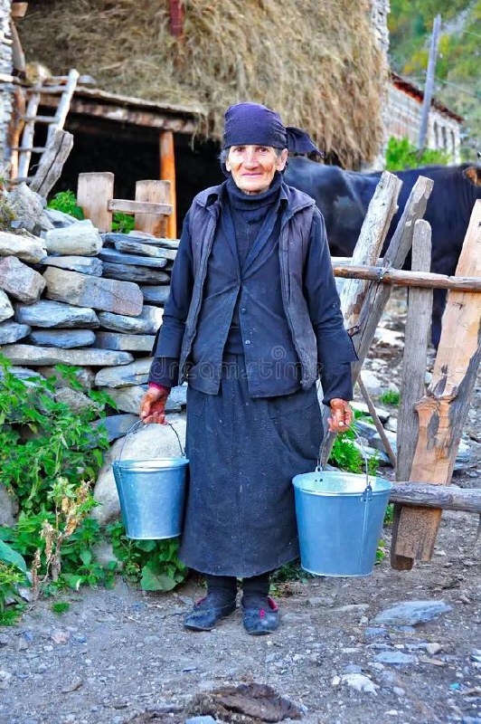 Пожилая женщина с двумя вёдрами у дома